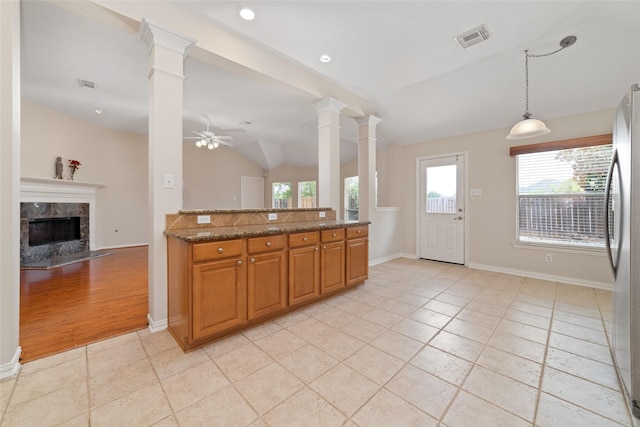 kitchen featuring pendant lighting, stainless steel fridge, stone counters, and ornate columns