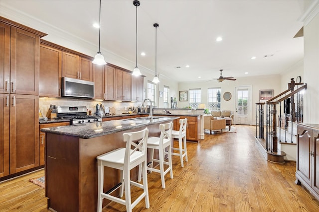 kitchen featuring a breakfast bar, sink, dark stone countertops, pendant lighting, and stainless steel appliances