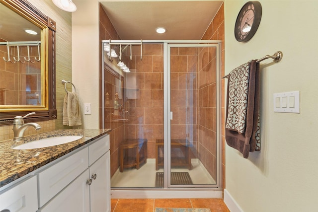 bathroom with tile patterned flooring, vanity, decorative backsplash, and walk in shower