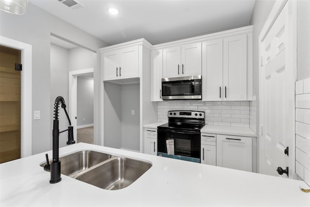 kitchen with black electric range oven, sink, decorative backsplash, and white cabinets