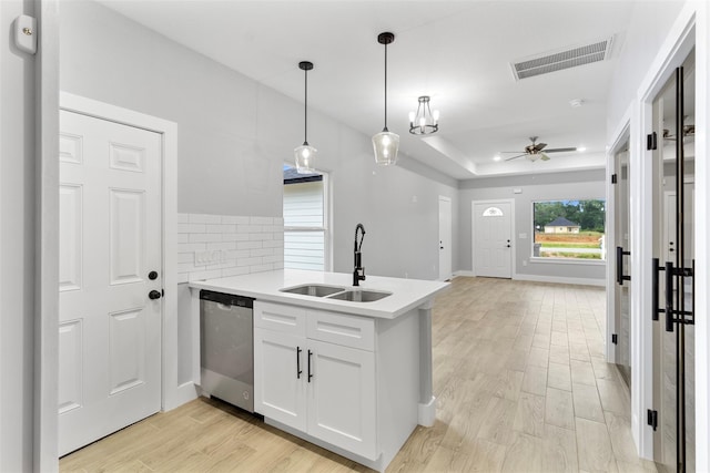 kitchen featuring sink, dishwasher, hanging light fixtures, a tray ceiling, and white cabinets