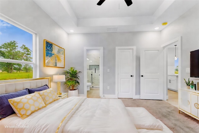 bedroom with light carpet, ensuite bath, visible vents, and a tray ceiling