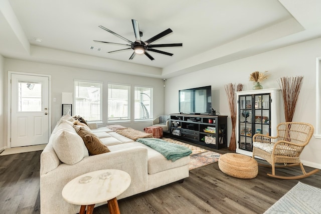 living room featuring dark wood-type flooring and a tray ceiling