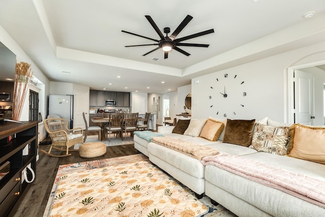 living room featuring ceiling fan, dark hardwood / wood-style flooring, and a raised ceiling