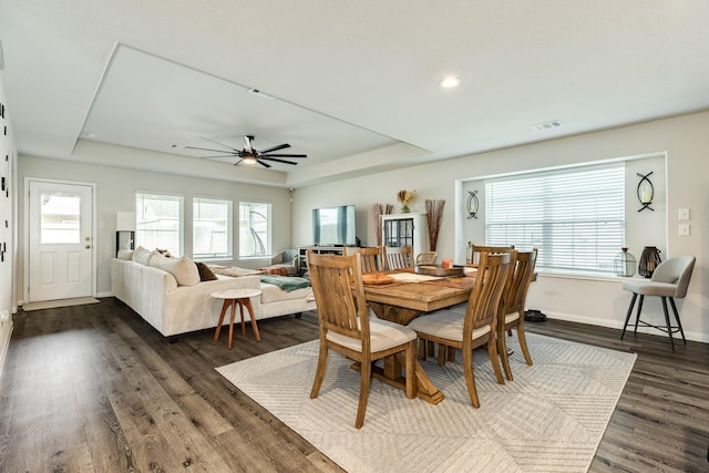 dining space featuring dark hardwood / wood-style floors, a wealth of natural light, and a raised ceiling