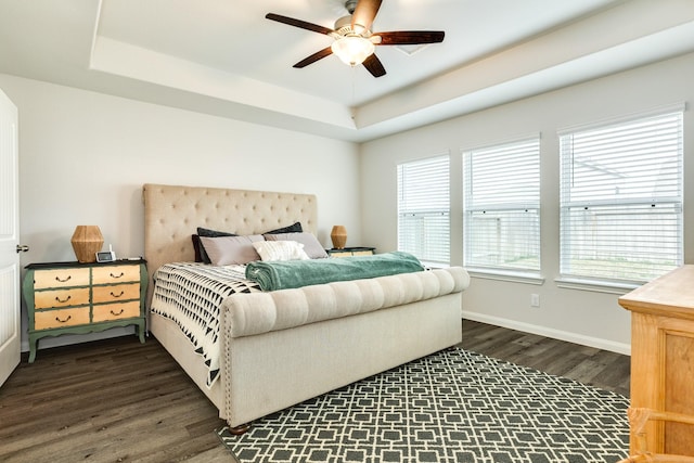 bedroom with dark wood-type flooring, ceiling fan, and a raised ceiling