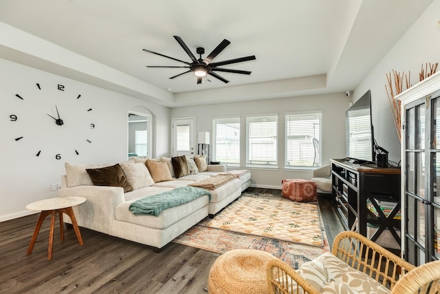 living room with ceiling fan, wood-type flooring, and a tray ceiling