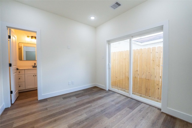 unfurnished bedroom featuring ensuite bathroom, sink, and light wood-type flooring