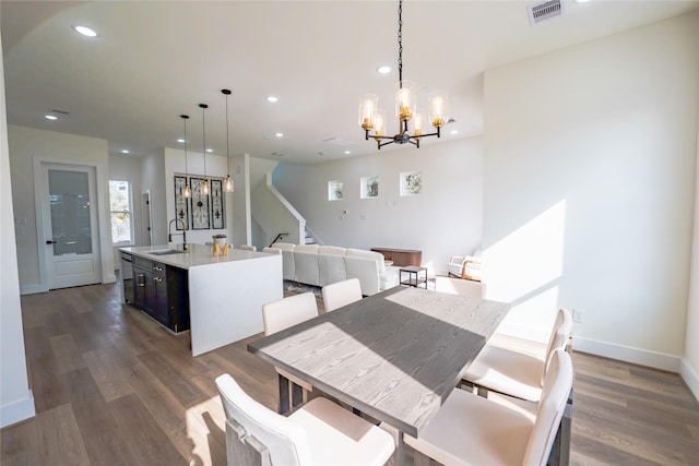 dining space with sink, a notable chandelier, and dark wood-type flooring