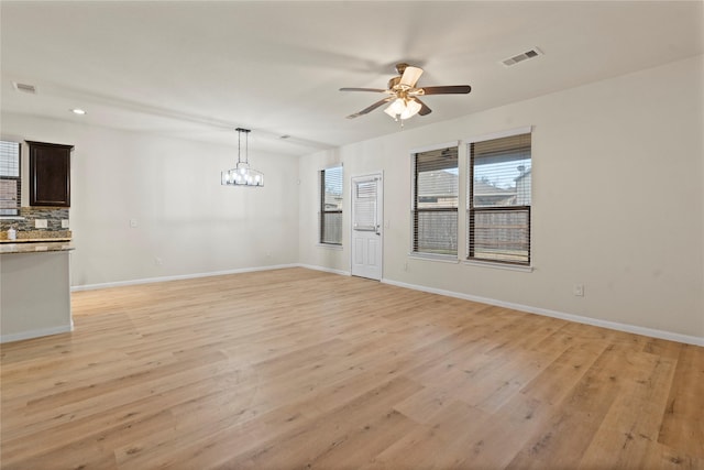 unfurnished room with ceiling fan with notable chandelier and light wood-type flooring