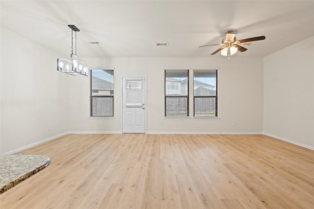 interior space featuring ceiling fan with notable chandelier, light hardwood / wood-style flooring, and a healthy amount of sunlight