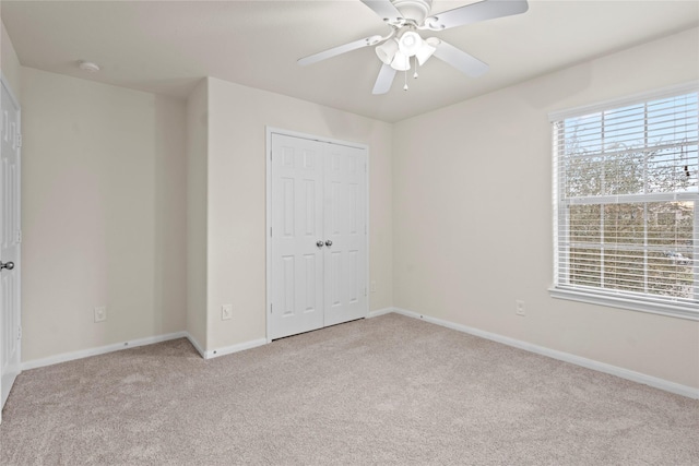 unfurnished bedroom with light carpet, a closet, and ceiling fan