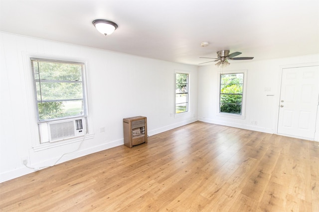 spare room featuring heating unit, light wood-style floors, a ceiling fan, cooling unit, and baseboards