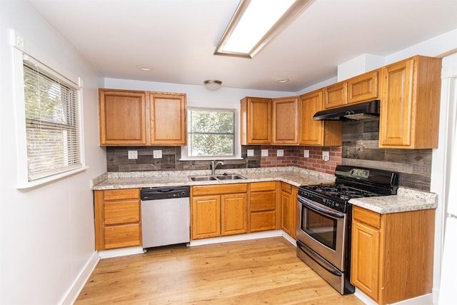 kitchen with stainless steel appliances, light wood-style floors, a sink, and under cabinet range hood