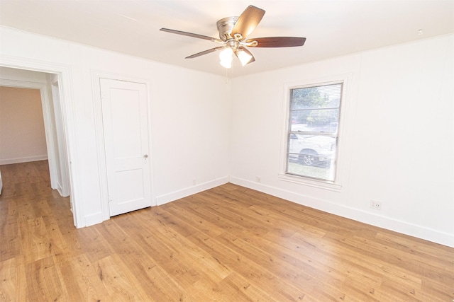 empty room featuring light wood finished floors, a ceiling fan, and baseboards