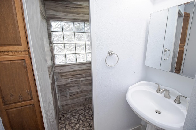 full bathroom with a sink and tiled shower