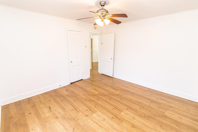 empty room featuring ornamental molding, light wood-type flooring, ceiling fan, and baseboards