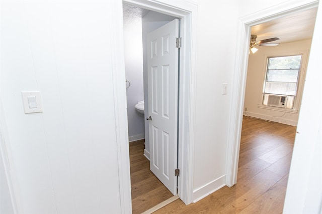 corridor featuring light wood finished floors, baseboards, and cooling unit