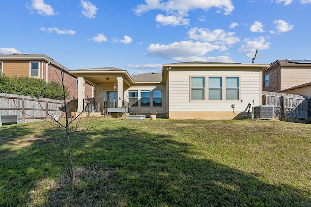 back of property featuring a yard and central AC