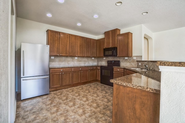 kitchen featuring black appliances, sink, decorative backsplash, dark stone counters, and kitchen peninsula