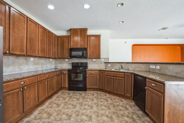 kitchen with light stone countertops, sink, decorative backsplash, and black appliances