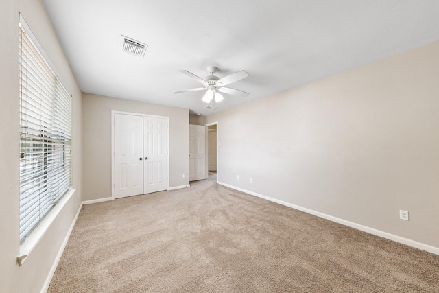 unfurnished bedroom featuring light colored carpet, a closet, and ceiling fan