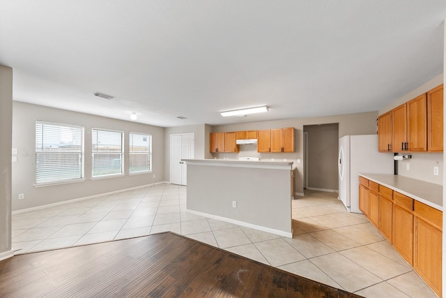 kitchen with a kitchen island, white fridge, and light tile patterned floors