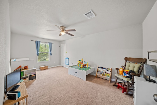 rec room with ceiling fan, light carpet, and a textured ceiling