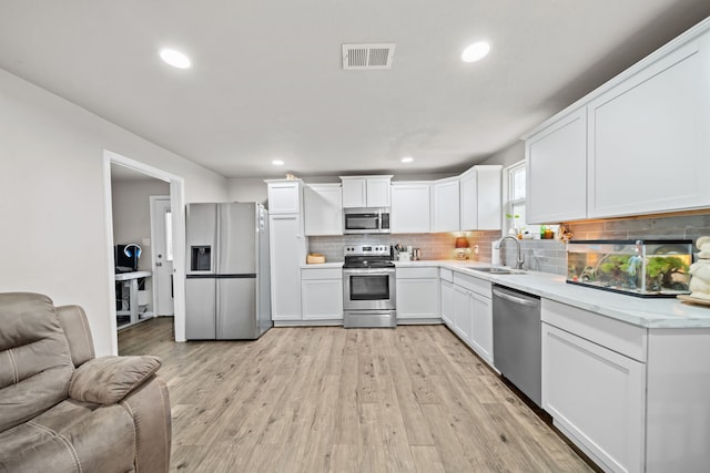 kitchen featuring sink, light hardwood / wood-style floors, white cabinets, and appliances with stainless steel finishes