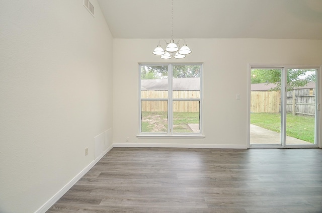 unfurnished dining area featuring wood-type flooring, a wealth of natural light, and a chandelier