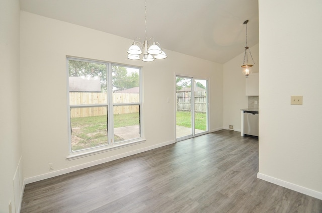 unfurnished dining area with vaulted ceiling, a chandelier, and hardwood / wood-style floors