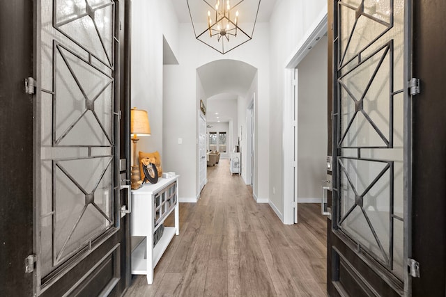 foyer featuring wood-type flooring, a chandelier, and a high ceiling