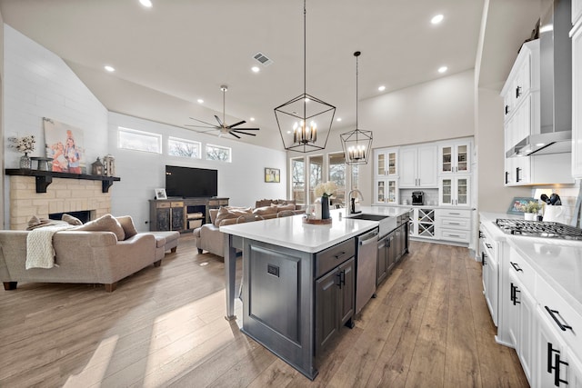 kitchen with white cabinetry, appliances with stainless steel finishes, a stone fireplace, and a kitchen island with sink