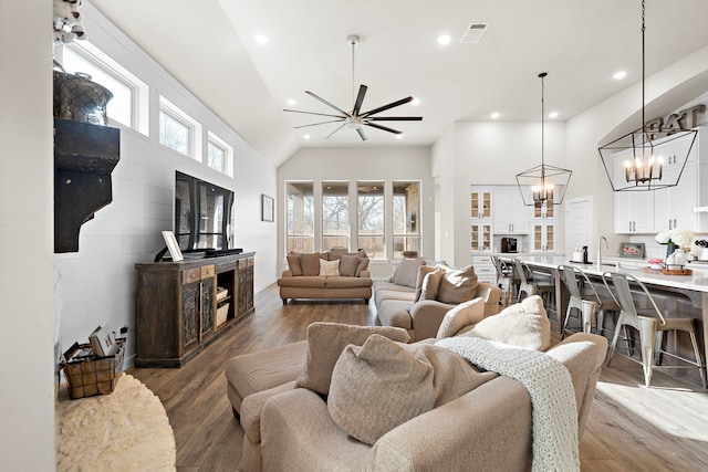 living room with hardwood / wood-style flooring, high vaulted ceiling, a chandelier, and sink