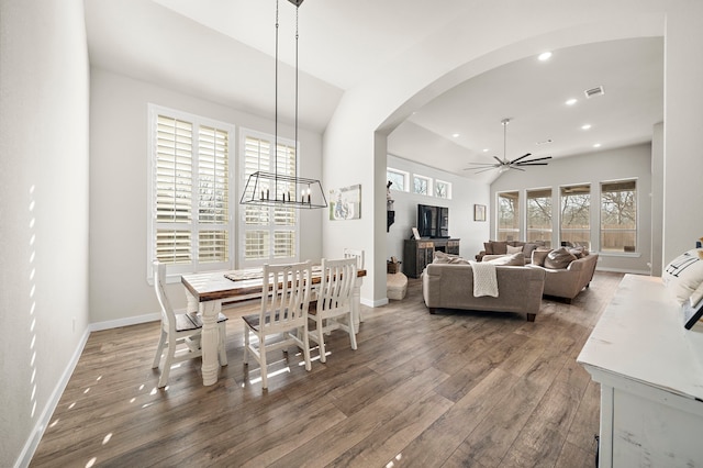 dining space with ceiling fan with notable chandelier, dark hardwood / wood-style floors, and a wealth of natural light