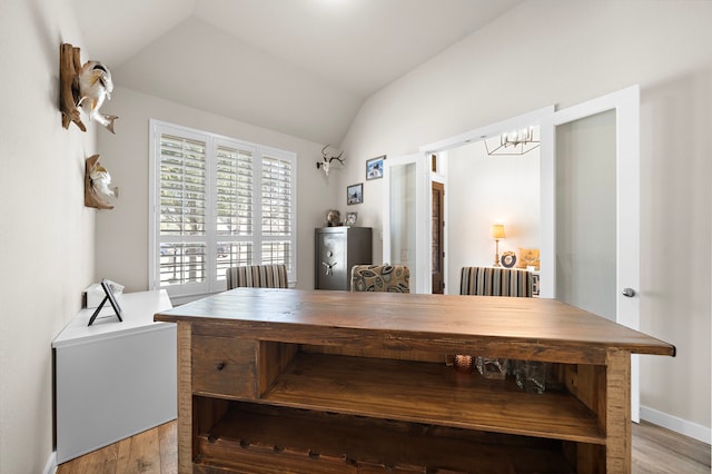 dining area with an inviting chandelier, vaulted ceiling, and hardwood / wood-style floors