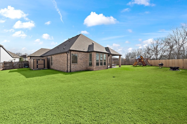 back of house with a playground, a yard, and a storage shed