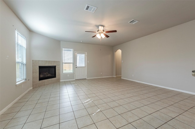 unfurnished living room with a tile fireplace, light tile patterned floors, and ceiling fan