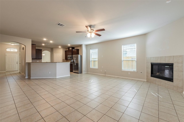 unfurnished living room featuring light tile patterned floors, a tile fireplace, and ceiling fan