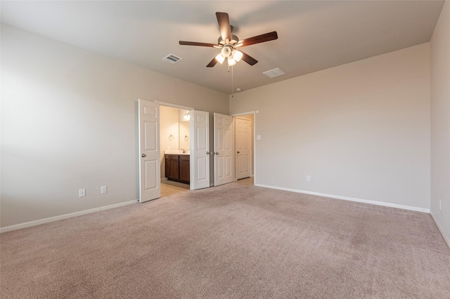 unfurnished bedroom featuring ceiling fan, light colored carpet, and ensuite bathroom