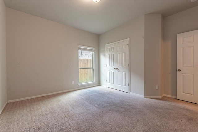 unfurnished bedroom with light carpet and a closet