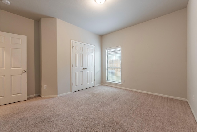 unfurnished bedroom featuring light colored carpet and a closet