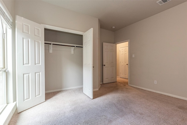 unfurnished bedroom featuring light carpet and a closet