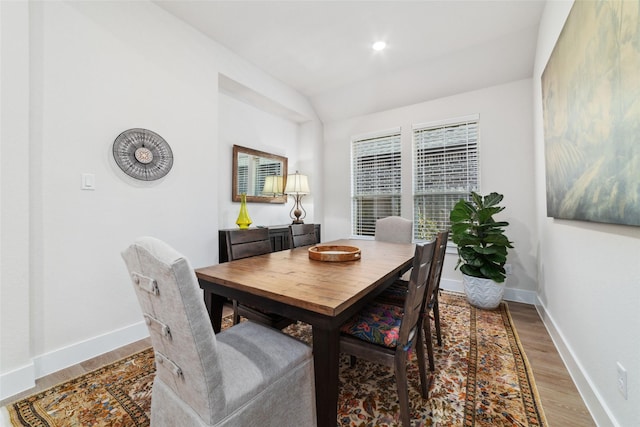 dining room with hardwood / wood-style floors and vaulted ceiling