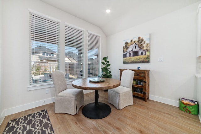 dining space with light wood-type flooring, vaulted ceiling, and a healthy amount of sunlight