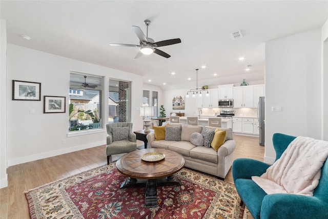 living room featuring ceiling fan, light hardwood / wood-style flooring, and sink