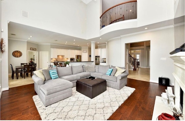 living area with visible vents, baseboards, stairway, dark wood-type flooring, and crown molding