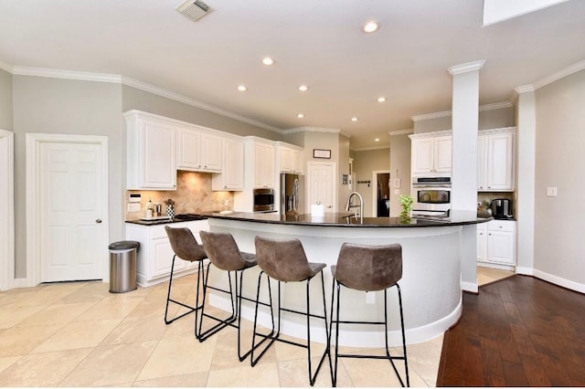 kitchen featuring stainless steel appliances, white cabinets, visible vents, and a large island