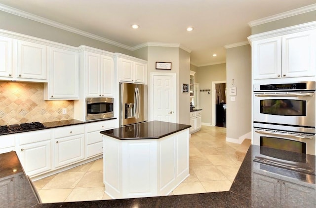 kitchen with stainless steel appliances, ornamental molding, dark countertops, and white cabinets