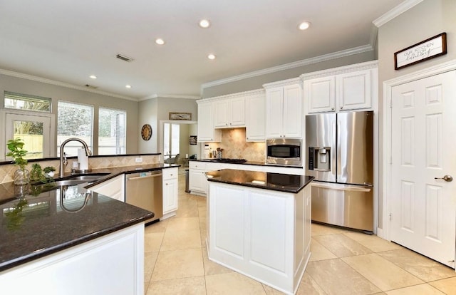 kitchen with stainless steel appliances, a sink, visible vents, a center island, and crown molding